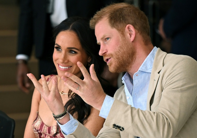 Le prince Harry (à droite), duc de Sussex, s'entretient avec son épouse Meghan Markle alors qu'ils assistent à un spectacle lors d'une visite au Centre national des arts de Bogota, le 15 août 2024.