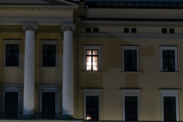 Une lumière est visible à une fenêtre du Palais royal alors que des personnes se rassemblent pour une veillée nocturne en l'honneur du roi Harald V de Norvège, sur la place du Palais à Oslo, tôt le 28 août 2026.