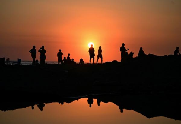 Des touristes profitent du soucher de soleil sur la plage d'El Tunco à La Libertad, au Salvador, le 13 février 2026