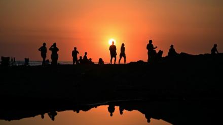 Des touristes profitent du soucher de soleil sur la plage d'El Tunco à La Libertad, au Salvador, le 13 février 2026