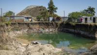 Des habitations surplombent une fosse à ciel ouvert creusée par des mineurs illégaux à la recherche de chrome à Bapong, un village minier de la province du Nord-Ouest (Afrique du Sud), le 25 août 2026