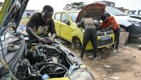 Des mécaniciens informels travaillent sur des moteurs de voiture dans le quartier d'Angré, à Abidjan, la capitale économique ivoirienne, le 21 juillet 2026.