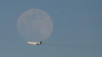 Un avion de la compagnie vénézuélienne Rutaca passe devant la lune, vu depuis l'aéroport international Simon Bolivar à Maiquetia, Venezuela, le 3 décembre 2025