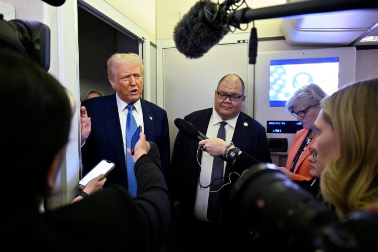 Le président américain Donald Trump s'entretient avec des journalistes, aux côtés du directeur de la communication de la Maison Blanche, Steven Cheung (c), à bord d'Air Force One, en route de Miami, en Floride, à la Maison Blanche, le 19 février 2025
