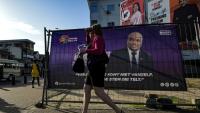 Une femme marche devant les panneaux de publicité électorale de candidats aux élections légisatives au Suriname, à Paramaribo le 23 mai 2025
