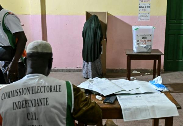 Une personne vote lors des élections législatives en Côte d'Ivoire, sous la surveillance d"un membre de la commission électorale indépendante, à  Abidjan le 27 décembre 2025