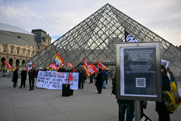 Des membres du syndicat CGT manifestent devant l'entrée du Louvre, à Paris, le 15 décembre 2025