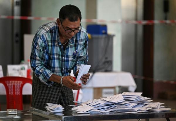 Un membre de la commission électorale birmane (UEC) trie des bulletins dans un bureau de vote de Rangoon, le 28 décembre 2025