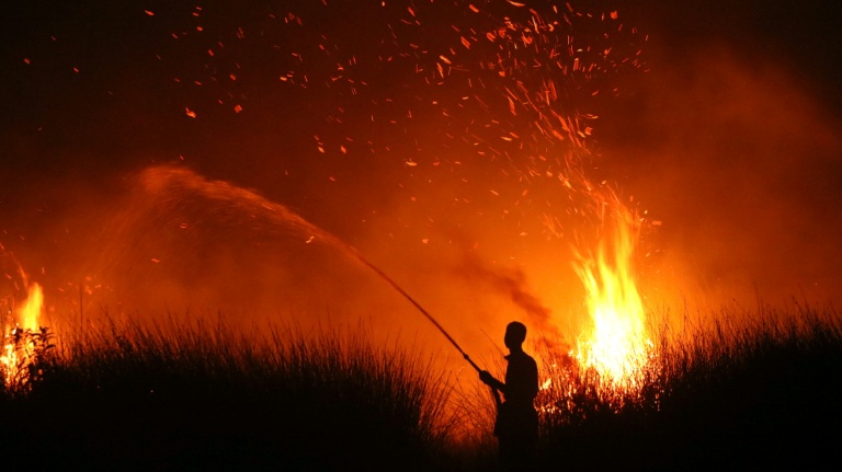 Cette photo prise le 11 août 2026 montre la silhouette d'un villageois tentant d'éteindre un incendie de forêt à Palangkaraya, dans le centre de l'Indonésie