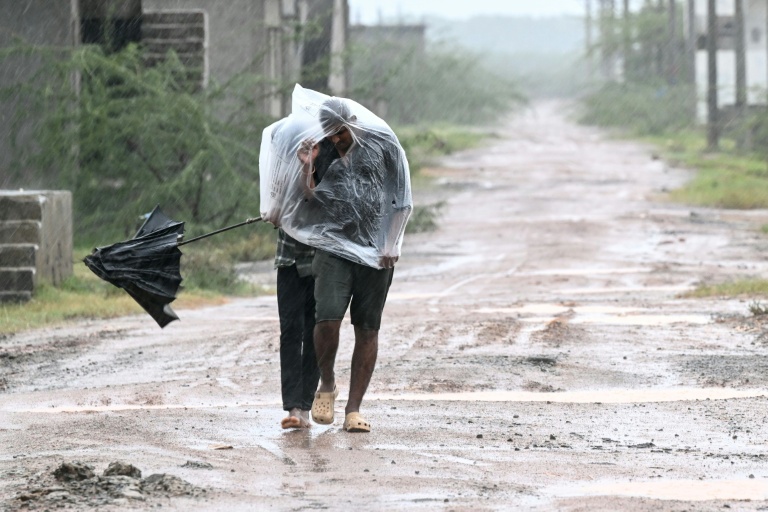 Des habitants se protègent avec un sac plastique d'une forte pluie à l'approche du cyclone Arnab, le 27 octobre 2026 à Kakinada, dans l'Etat de l'Andhra Pradesh, en Inde