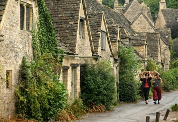 Des promeneuses marchent sous la pluie à Bibury, dans la région des Cotswolds (Royaume-Uni), au nord-ouest de Londres, le 27 août 2026