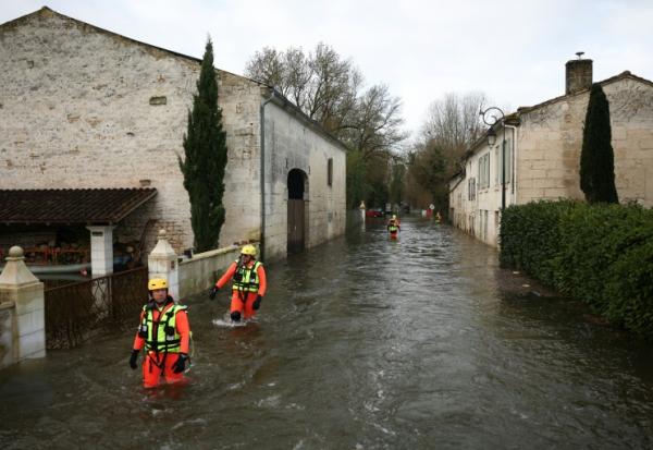 Des sauveteurs en mer dans une rue inondée lors d'une opération visant à évacuer des habitants isolés à Courcoury, en Charente-Maritime, le 21 février 2026