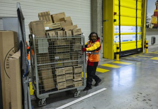 Un employé pousse un conteneur de colis dans un entrepôt DHL à Lesquin, près de Lille, le 12 novembre 2025