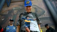 Un fan de football portant un t-shirt à l'effigie de la légende argentine Diego Maradona fait la queue devant le stade La Bombonera pour assister à la veillée funèbre de l'entraîneur argentin Miguel Angel Russo à Buenos Aires, le 9 octobre 2025. 