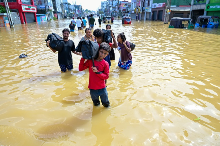 Des habitants emportent leurs biens dans une rue inondée de la banlieue de Colombo, la capitale du Sri Lanka, le 30 novembre 2025
