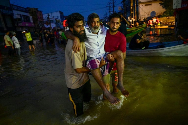 De jeunes hommes portent une personne âgée dans une rue inondée de Wellampitiya, dans les faubourgs de Colombo, la capitale du Sri Lanka, le 30 novembre 2025