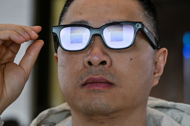 Cette photo, prise le 13 novembre 2025, montre un homme examinant une paire de lunettes Rokid dotées d'un écran et d'une caméra utilisant l'intelligence artificielle (IA) et la réalité augmentée (RA), lors d'une présentation à Hangzhou, dans la province du Zhejiang, en Chine orientale