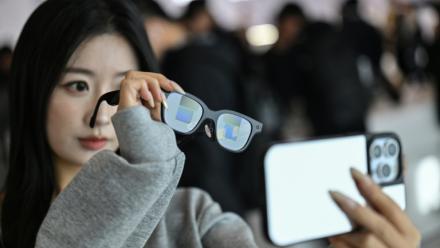 Cette photo, prise le 13 novembre 2025, montre une femme examinant une paire de lunettes Rokid dotées d'un écran et d'une caméra utilisant l'intelligence artificielle (IA) et la réalité augmentée (RA), lors d'une présentation à Hangzhou, dans la province du Zhejiang, en Chine orientale