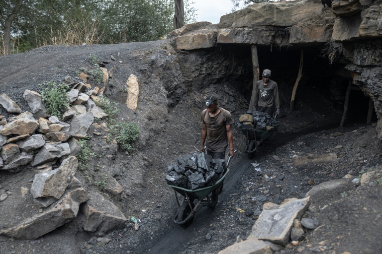 Des mineurs poussent des brouettes chargées de charbon à l'extérieur de la mine illégale de Golfview, à Ermelo en Afrique du Sud, le 25 septembre 2025