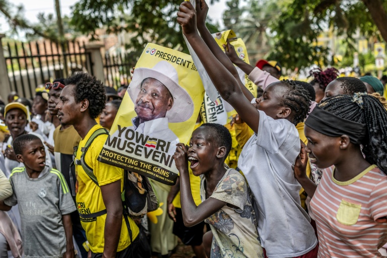 De jeunes partisans du président ougandais sortant Yoweri Museveni brandissent des affiches électorales et chantent des slogans à son dernier meeting de campagne, le 13 janvier 2026 à Kampala