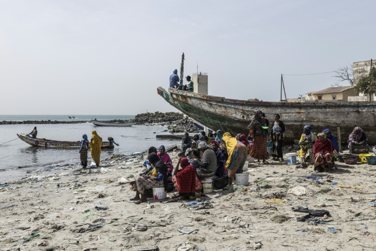 Des marchands de poisson sur la plage d'un quai de pêche à Rufisque, le 3 mars 2026, au Sénégal