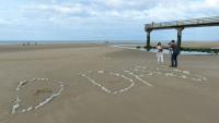 Une famille sur "Omaha Beach", où le mot "D-Day" a été tracé à l'aide de galets, à  Vierville-sur-Mer, dans le Calvados, lors des célébrations du 75e anniversaire du Débarquement en juin 2019