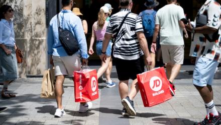 Des passants portent des sacs de courses à Paris, le 25 juin 2025, premier jour des soldes d'été en France