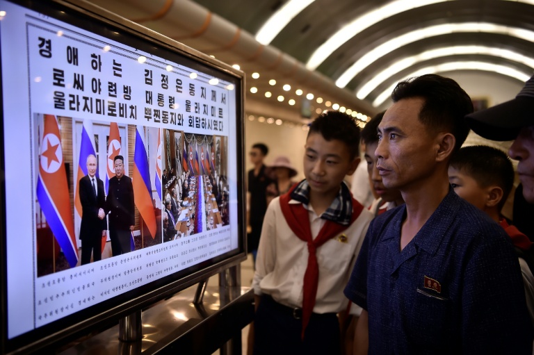 Des passants lisent le journal Rodong Sinmun exposé dans une station de métro de Pyongyang, le 20 juin 2024