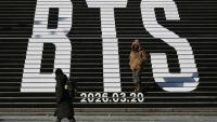 Des piétons le long d'escaliers décorés du logo du groupe de K-pop BTS, près de la place Gwanghwamun à Séoul, le 14 janvier 2026