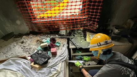 Sur cette photo prise et transmise le 23 avril 2026 par Bowie Chan, un habitant de Wang Fuk Court, son épouse Annie Tse fouille les tiroirs d'un meuble de leur appartement endommagé par l'incendie de novembre, à Hong Kong