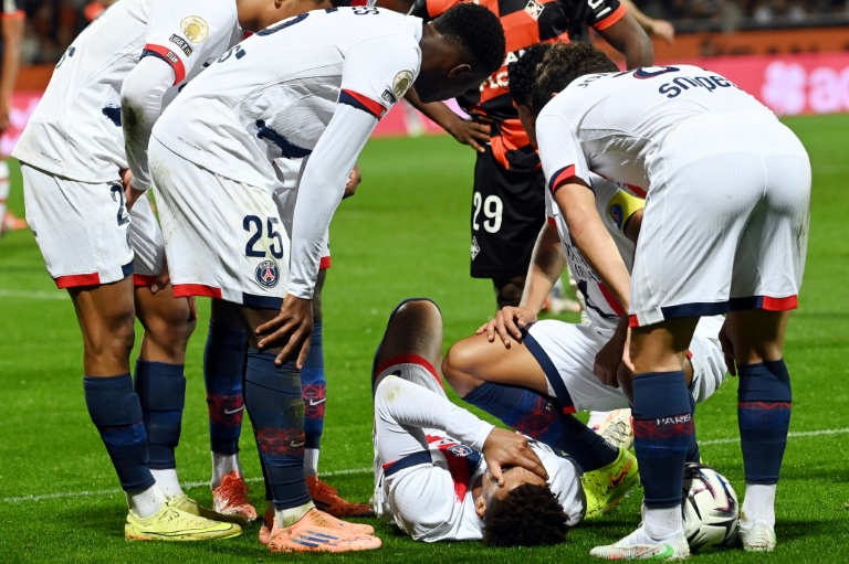 Le milieu de terrain du PSG Désiré Doué (C) victime d'une blessure à la cuisse et entouré de ses coéquipiers, à Lorient, le 31 octobre 2025