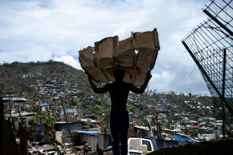 Un homme muni de tôles pour reconstruire sa maison dans le bidonville de Cavani, à Mamoudzou, à Mayotte, le 2 janvier 2025