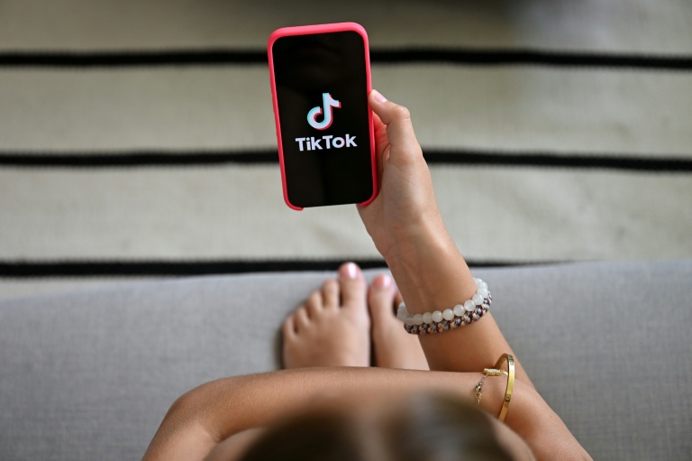 Une jeune fille tient son smartphone, sur lequel apparaît le logo du réseau social Tik Tok, le 7 juillet 2026 à Bruxelles 