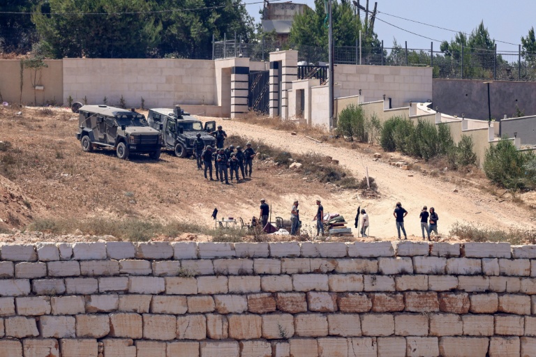 Des soldats israéliens au dessus de colons à Des soldats israéliens (en haut) montent la garde aux côtés de colons devant des maisons palestiniennes dans le village de Qusra, au sud de Naplouse, en Cisjordanie occupée, le 12 août 2026