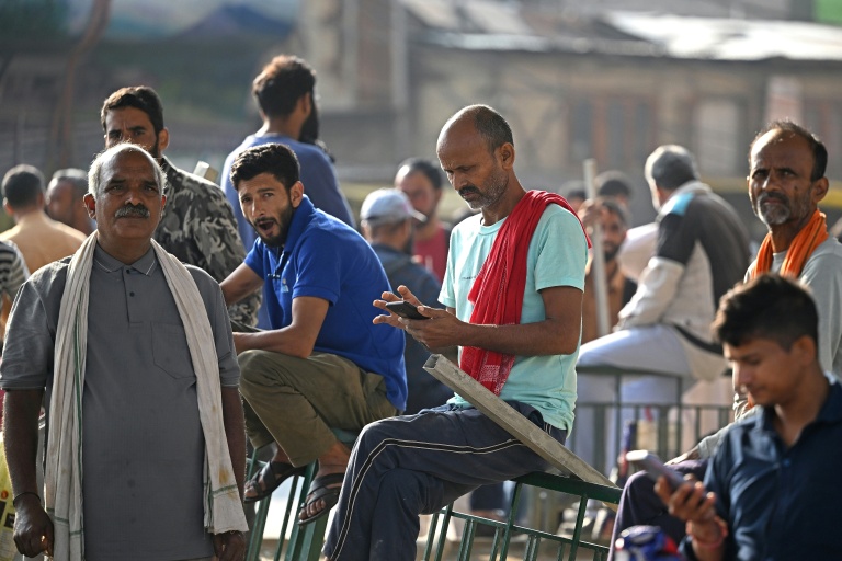 Des ouvriers migrants indiens attendant des clients à la recherche de main-d’œuvre journalière sur un marché de Srinagar, le 24 août 2026
