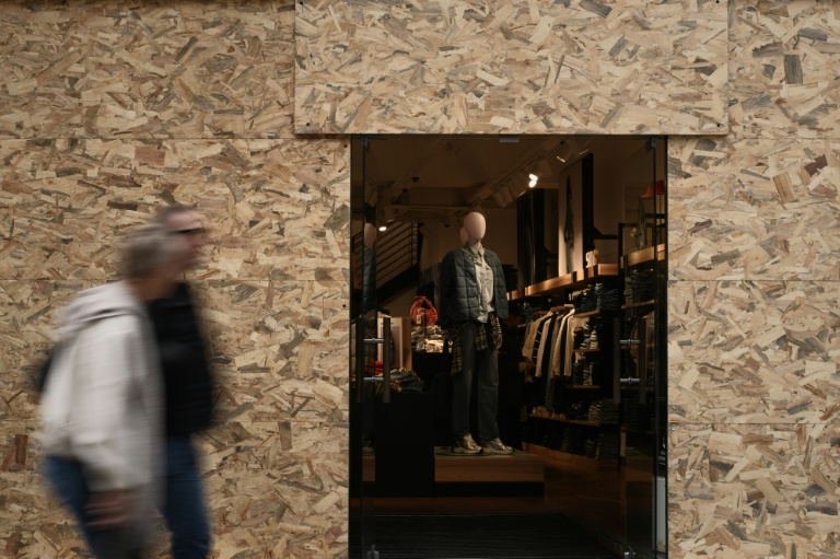 Des passants devant un magasin de vêtements dont les vitrines ont été protégées en prévision d'une nouvelle manifestation, le 24 octobre 2026 à Bordeaux 