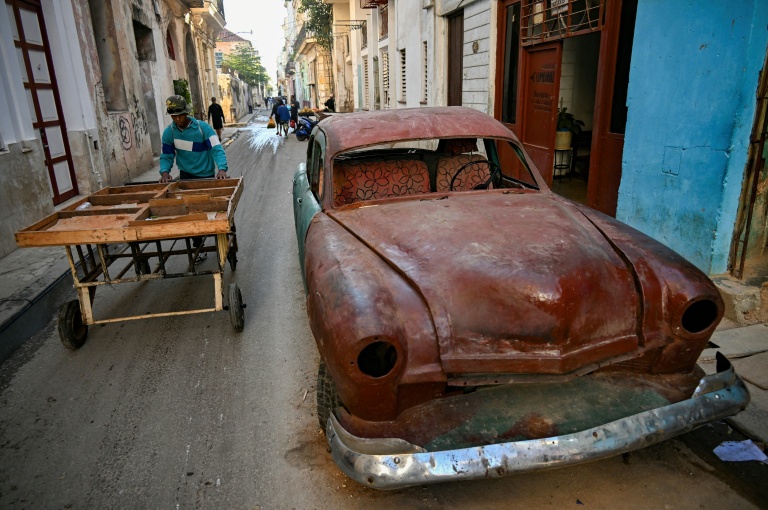 Un homme pousse une charrette près d'une vieille voiture dans une rue de La Havane, le 4 mai 2026