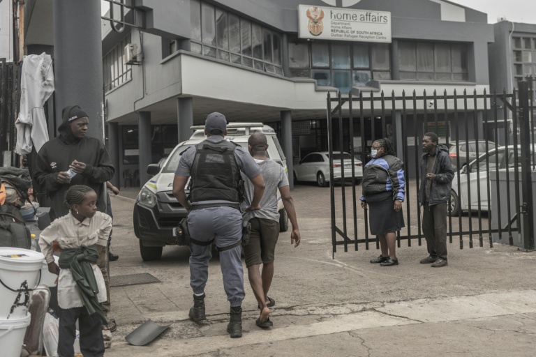 Un policier sud-africain interpelle un ressortissant étranger soupçonné d’être en situation irrégulière lors d’une opération de contrôle et de fouille dans le centre de Durban, le 29 juin 2026