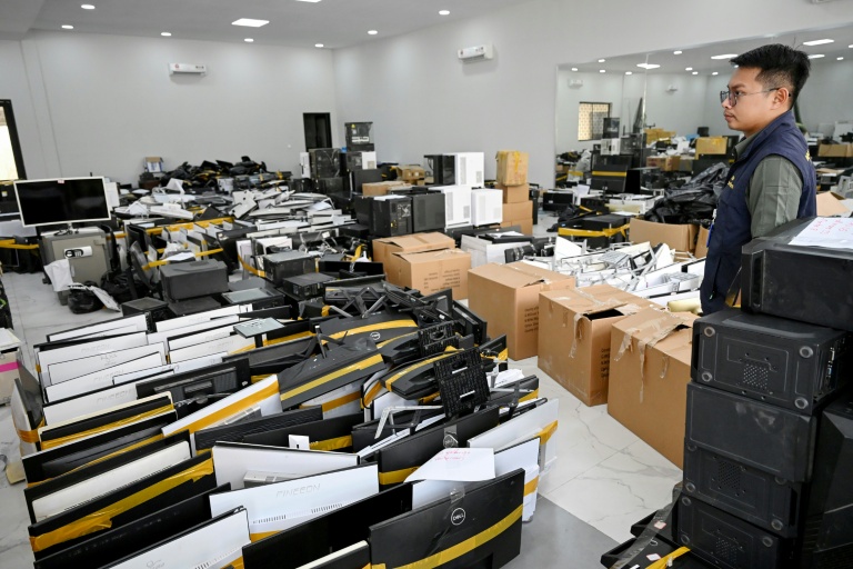 Un policier à côté de matériel saisi dans des centres d’opérations de cyberarnaques, au commissariat de la police municipale de Phnom Penh, le 11 mars 2026 au Cambodge