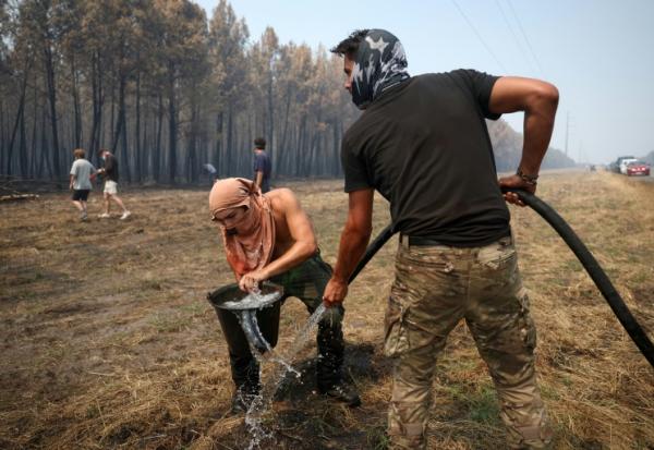 Un volontaire remplit un seau d’eau pour aider à lutter contre l’incendie dans une forêt à Lanton, à l’ouest de Bordeaux, le 29 juillet 2026, lors des feux de forêt dans le département de la Gironde, dans le sud-ouest de la France