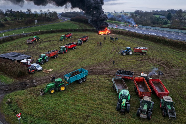 Des agriculteurs allument un feu alors qu'ils participent, avec leurs véhicules, à un blocage d'autoroute, à Poilley, dans l'ouest de la France, le 5 janvier 2026