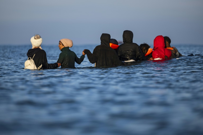 Des migrants avancent dans l'eau pour monter à bord d'un bateau de passeurs et tenter de traverser la Manche, au large de la plage de Gravelines, le 27 septembre 2025 dans le Nord