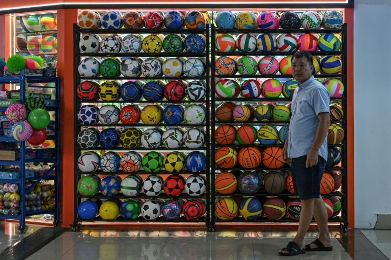 Un homme passe devant un stand d'articles de sport vendant des ballons au marché international de Yiwu, dans la province du Zhejiang, dans l'est de la Chine, le 17 septembre 2025