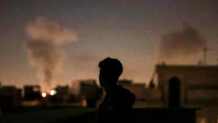 Une personne regarde la fumée de frappes aériennes sur Téhéran, le 4 mars 2026 en Iran