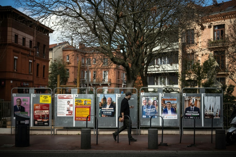 Un piéton passe devant les panneaux électoraux à Toulouse, le 10 mars 2026