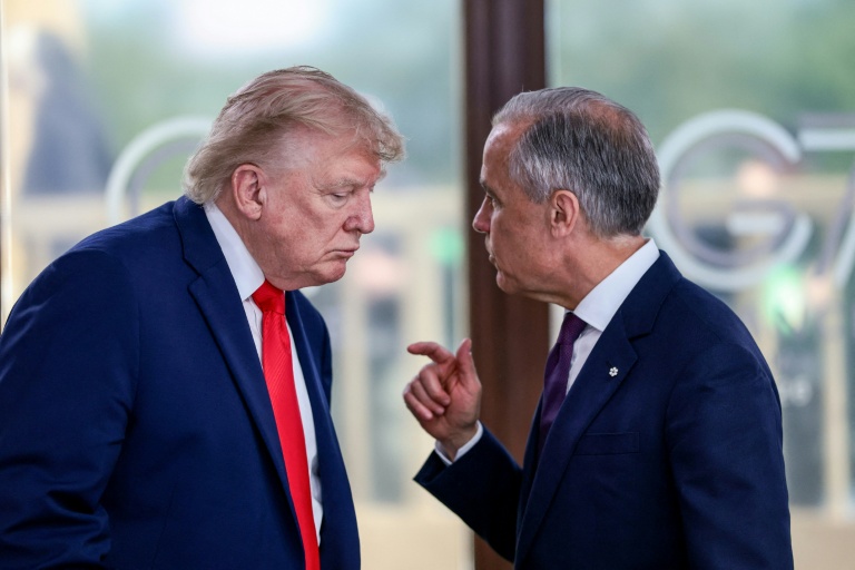 Le président américain Donald Trump (g) s'entretient avec le Premier ministre canadien Mark Carney lors d'un déjeuner de travail dans le cadre du sommet du G7, à Évian, le 16 juin 2026 dans l'est de la France