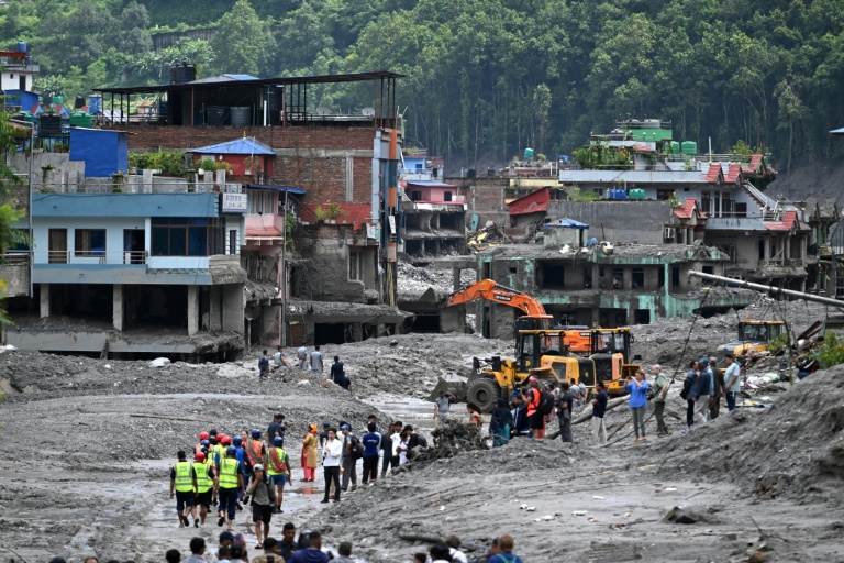 Des pelleteuses dégagent la boue et les décombres après la crue destructrice qui a fait au moins 633 morts à la frontière entre le Népal et la Chine, le 29 août 2026 à Dhunge Bazaar, dans le district népalais de Nuwakot  