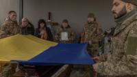 Des soldats ukrainiens portent un drapeau ukrainien au-dessus du cercueil d'un de leurs camarades tués près d'Avdiïvka, le 24 février 2024 à Boutcha en Ukraine