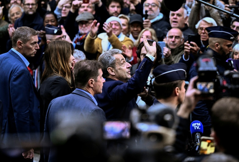 L'ancien président Nicolas Sarkozy salue ses partisans rassemblés devant sa résidence qu'il quitte pour se rendre à la prison de la Santé, le 21 octobre 2025 à Paris