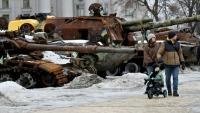 Un couple et un enfant à vélo se promènent dans l'exposition en plein air d'équipements militaires russes détruits à Kiev, le 15 février 2026